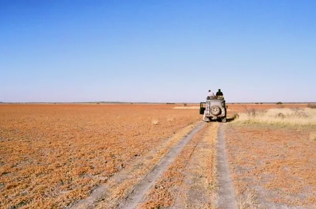 A Land Rover Defender on red Kalahari earth — the operator's vehicle, used not posed.